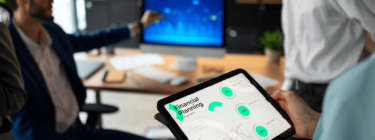 A imagem mostra um profissional segurando um dispositivo mobile e olhando para um computador que mostra dados, simbolizando a cultura data driven.